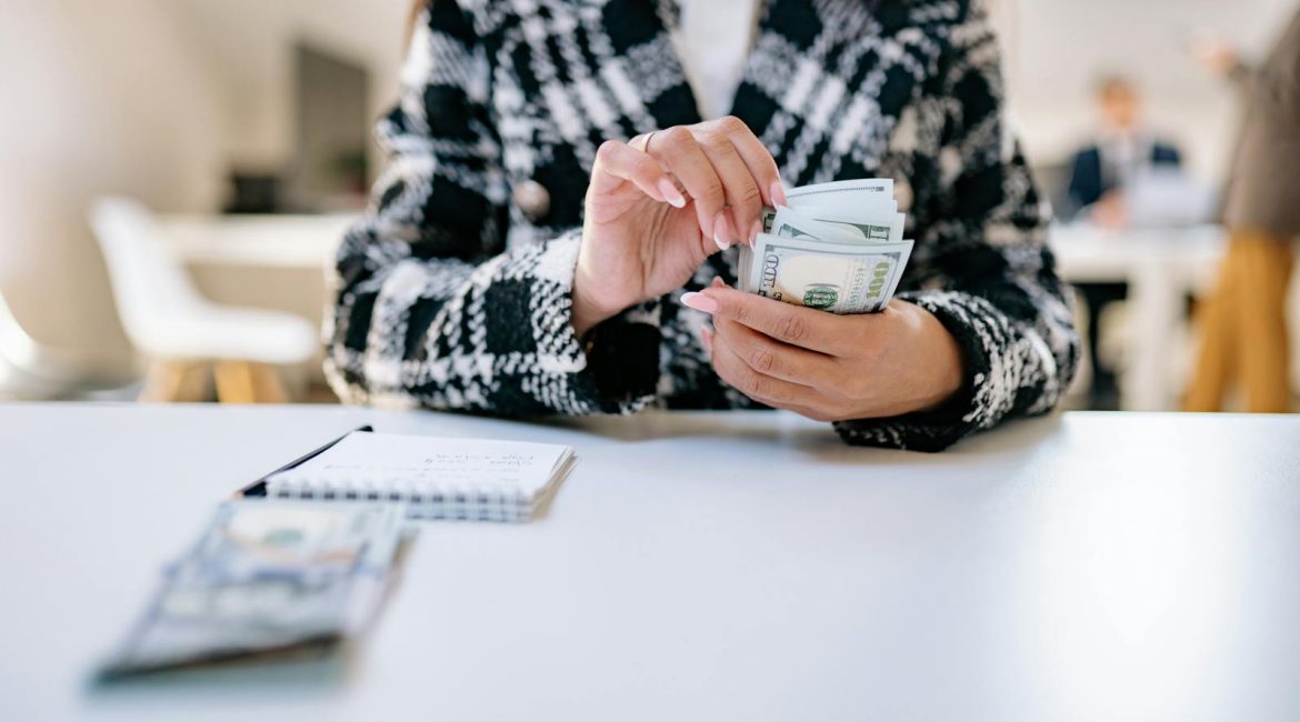 A close-up of a woman counting US dollars in an office environment, symbolising financial management