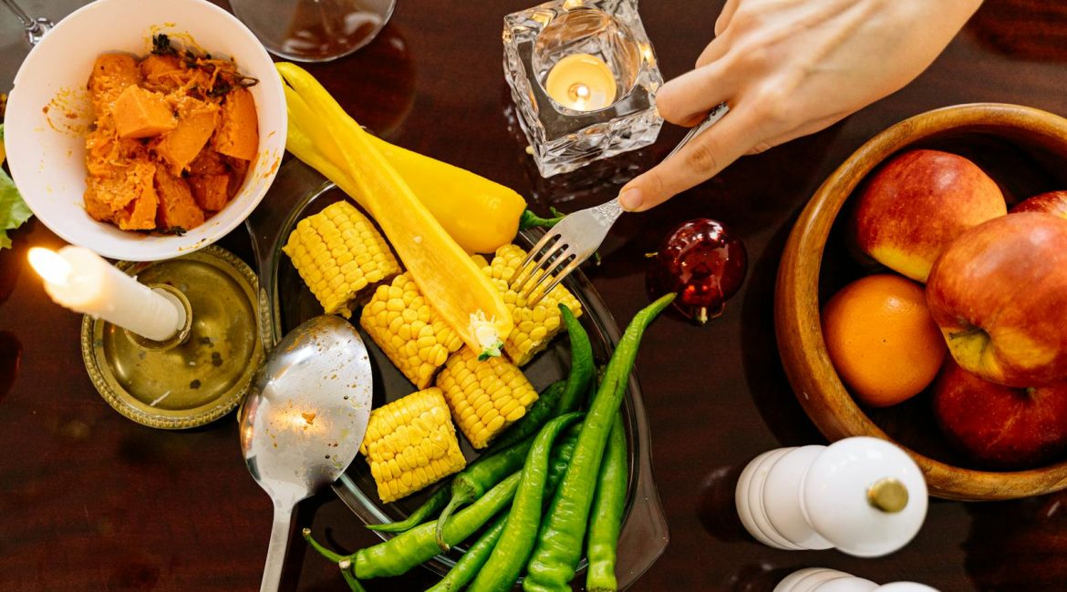 Colorful dinner setting with fresh vegetables, candles, and apples for a cosy autumn feast